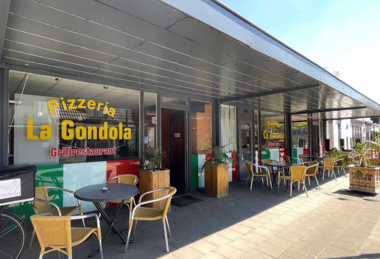 Gevel van La Gondola met de gele letters Pizzeria La Gondola, de tricolore op het glas en het terras