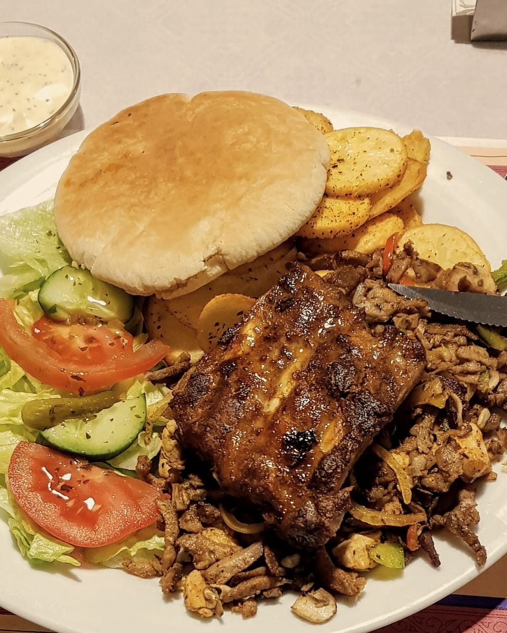 Grillschotel met spareribs, gekruid vlees, pita, gebakken aardappeltjes en salade